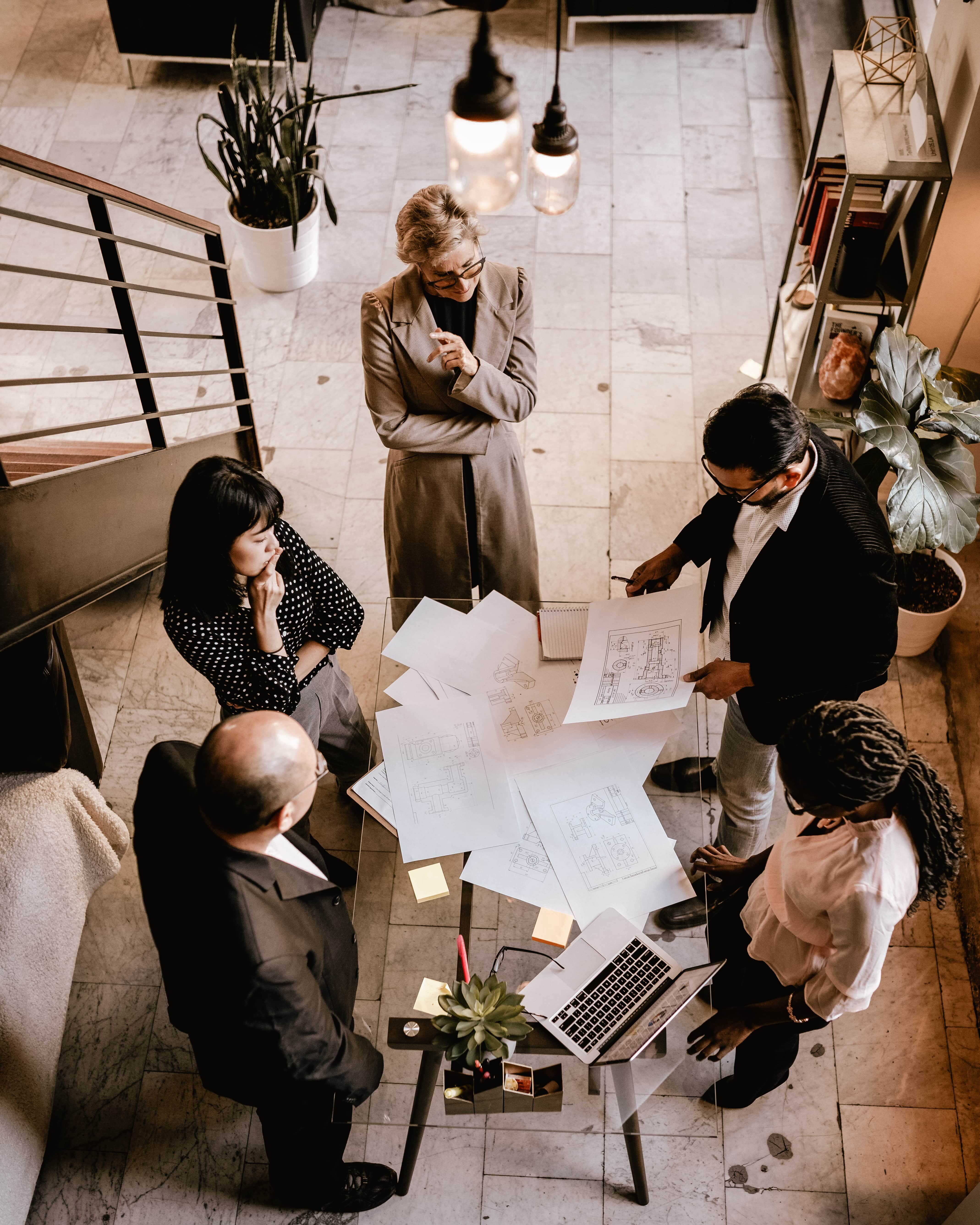 People in an office discussing real estate documents around a table with papers and a laptop