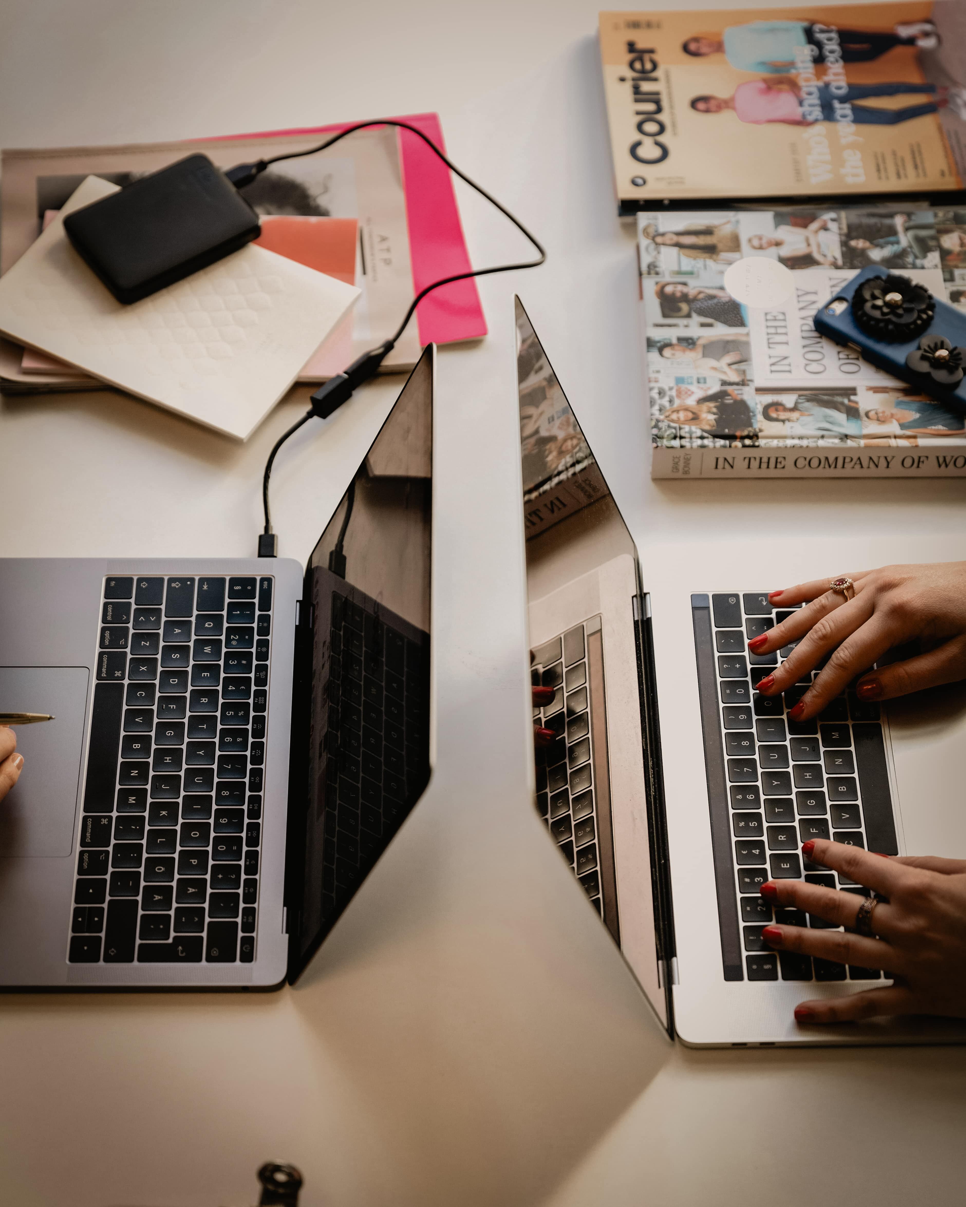 Magazines and two laptops on a desk in a marketing workspace